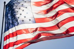 Backlit American Flag Waving In Wind Against a Deep Blue Sky
