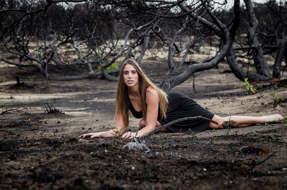 Woman posing on ground near dry trees