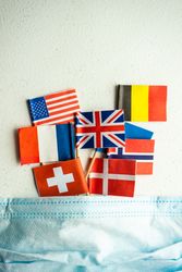 COVID-19 concept  with face mask and flags of countries emerging