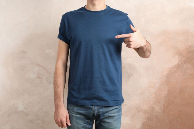 Men in blank blue t-shirt against brown background, space for text