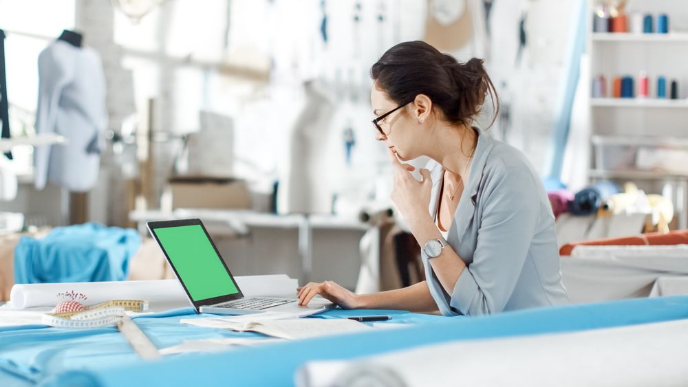Woman fashion, designer,  Sitting at Her Desk Working on Laptop with Green Screen, Taking Notes.