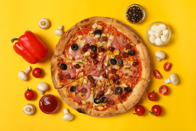 Tasty pizza and ingredients on yellow background