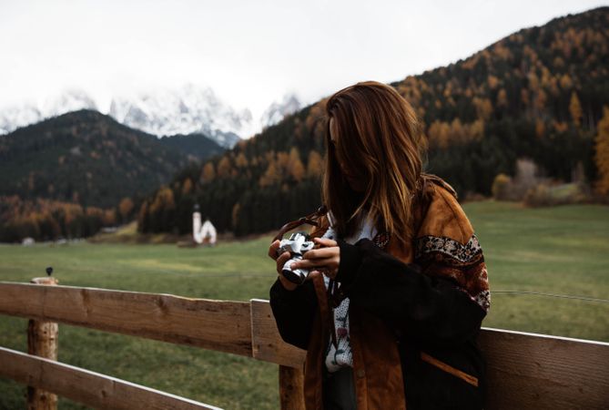 Woman with camera standing near church in mountains