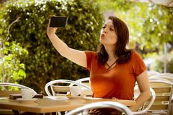 Woman talking selfie with smartphone in cafe