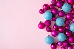Pink and blue festive baubles on side of pink background