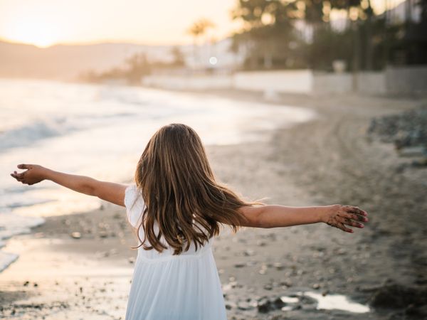 Excited girl running along beach in daylight