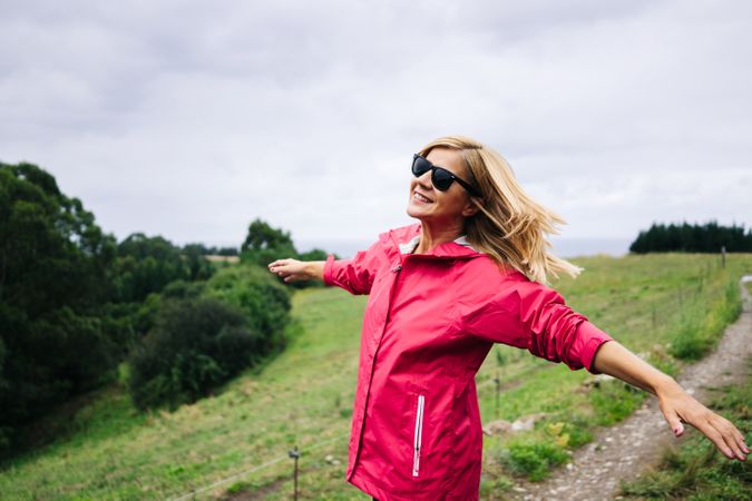 Cheerful woman enjoying countryside landscape stretching hands