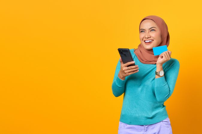 Muslim woman happy and holding credit card and smart phone