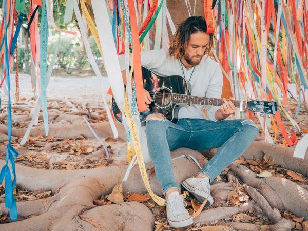 Man sitting under tree playing guitar