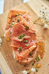 Delicious toast with prosciutto and olive oil served on wooden board