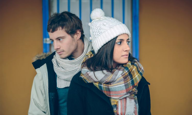 Couple wearing winter clothes standing and looking sideways outdoors