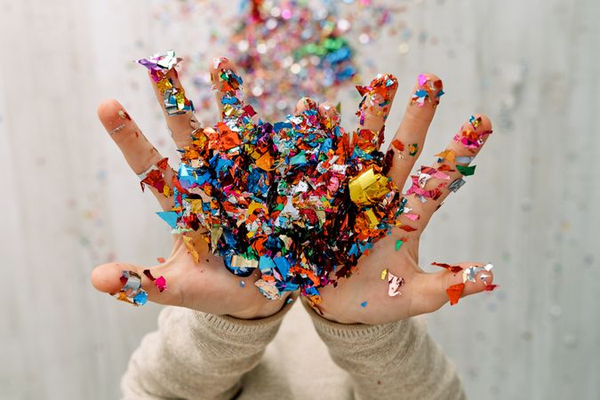 Child with multicolored confetti in hands