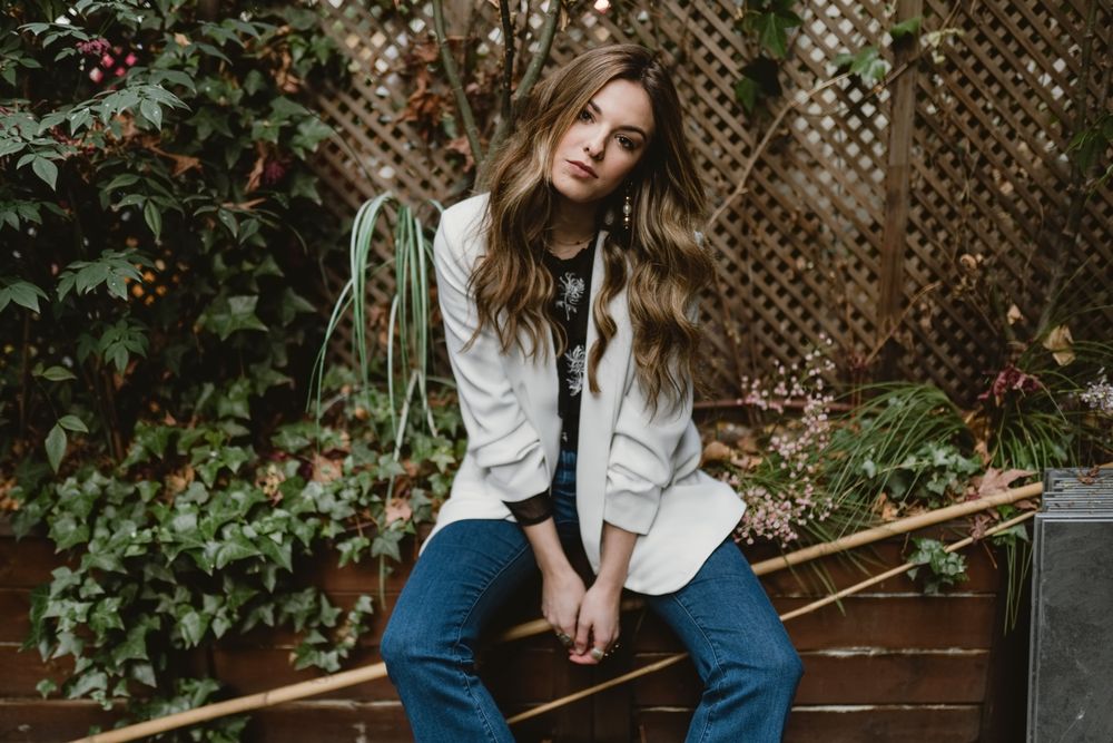Woman sitting on planter in garden