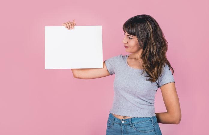 Woman holding a blank sign against a pink background