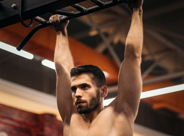 male athlete doing pull ups in a gym