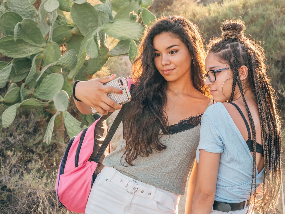 Smiling trendy young women taking selfie at countryside
