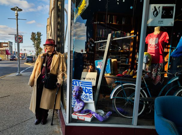 Man with cane and trench coat pauses outside a shop in Hamtramck, Michigan