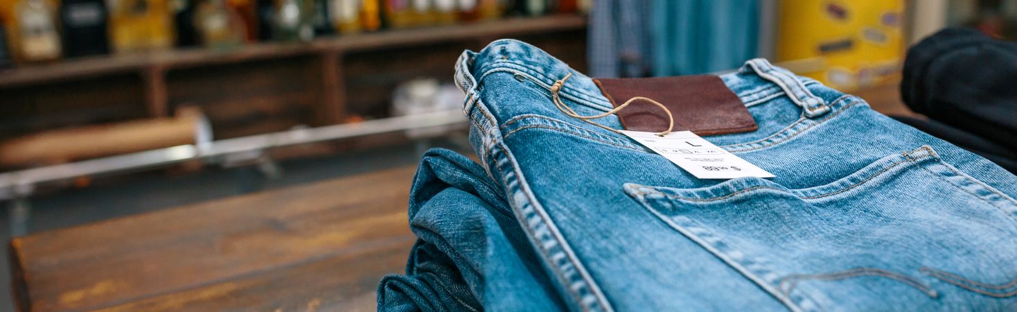 Blue jeans pants stacks over counter on vintage clothes shop with left copy space