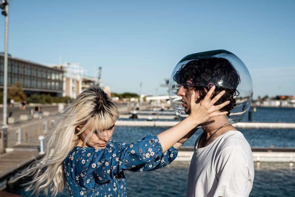 Woman touching fish bowl on head of boyfriend