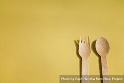 Disposable fork & spoon on yellow background with copy space bE6GV0