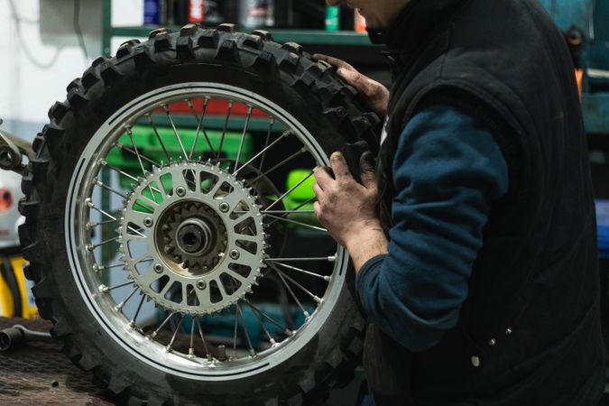 Crop mechanic changing motorbike chain in workshop