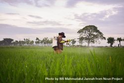 Farmer in Indonesia spraying plants in long grass field bGRN7X