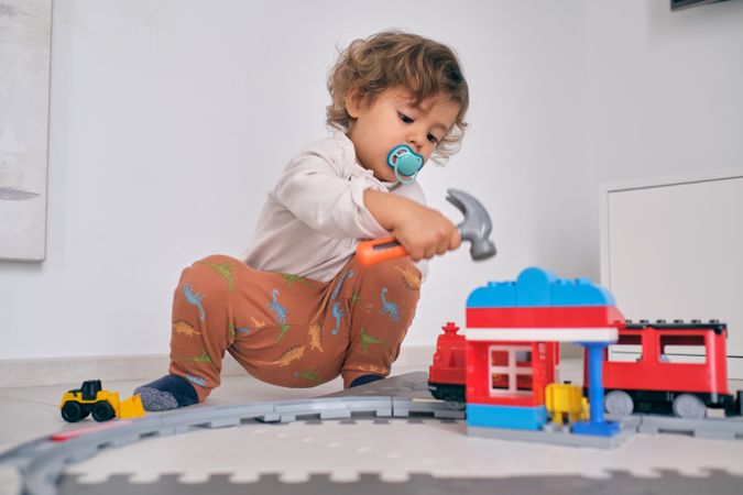 Child playing with toy train station at home