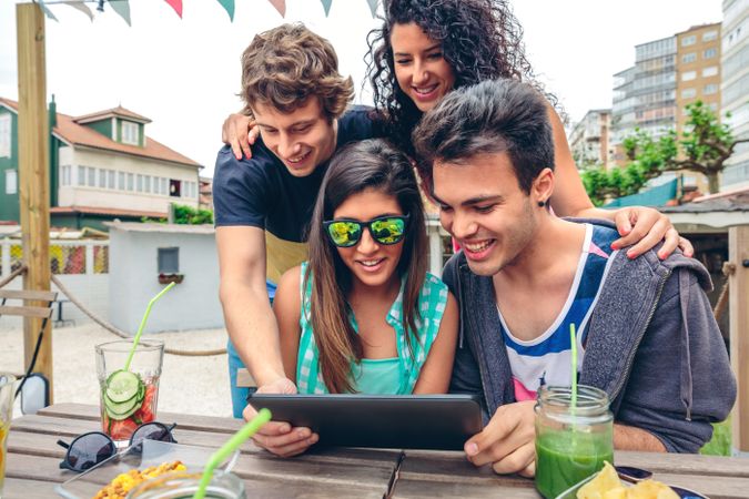 Friends sitting outside checking digital tablet