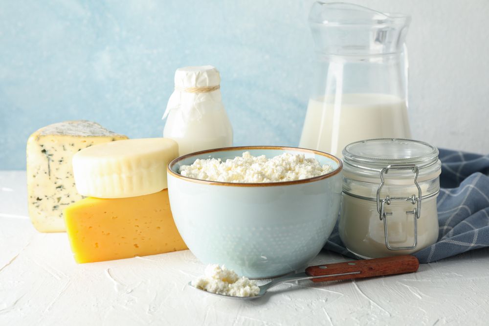 Different dairy products on neutral table against blue background