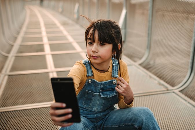 Funny girl taking selfie on smartphone on walkway