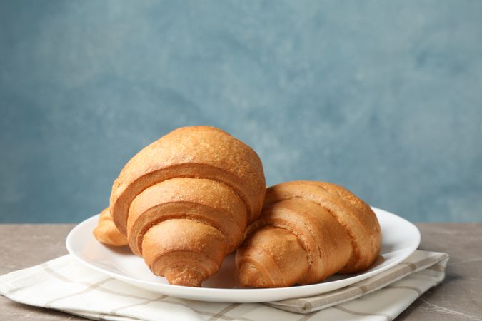 Plate with croissants on grey table, in blue room space for text