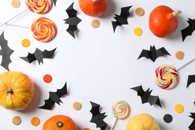 Candy, decorative bats and pumpkins on plain background, space for text