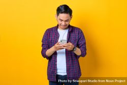 Asian man in plaid shirt  looking down at smartphone 5rXapb
