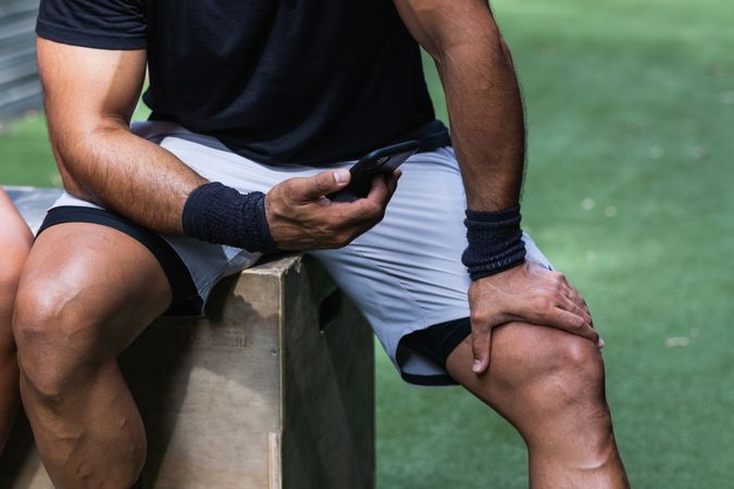 Anonymous fit man browsing smartphone during training