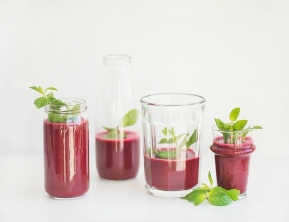 Red juice poured in glasses and jars garnished with mint