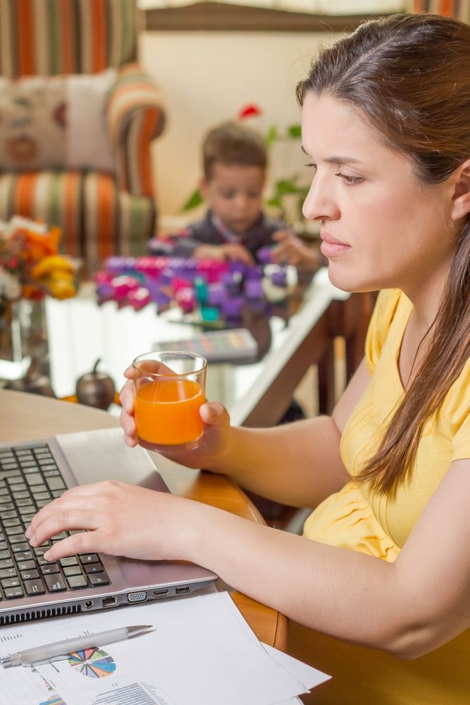Pregnant mother working in home office with son