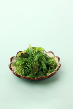 Bowl of Japanese seaweed salad on mint background