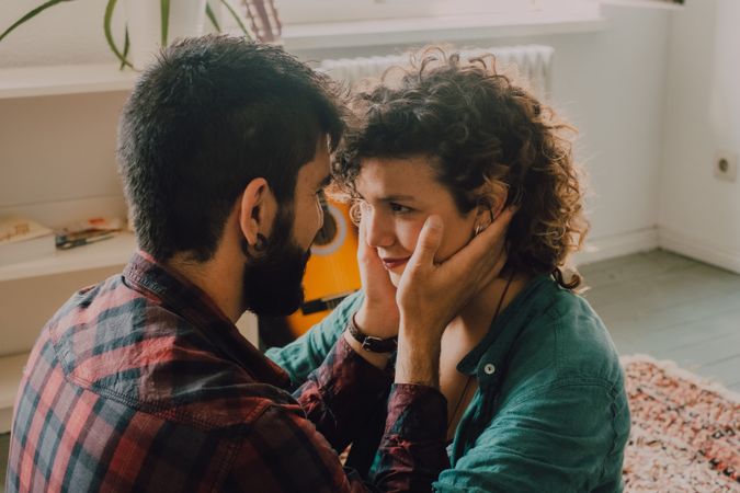 Loving couple embracing while sitting on apartment floor