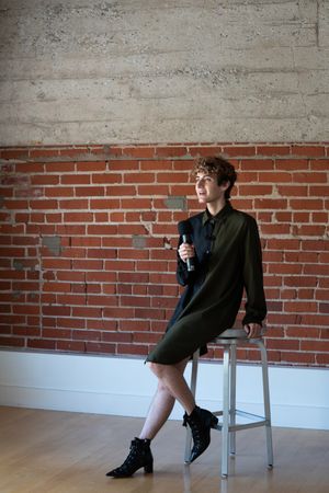 Nonbinary person perched on chair giving a talk