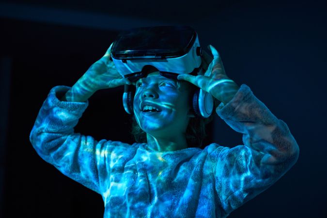Excited child taking off VR goggles and looking away