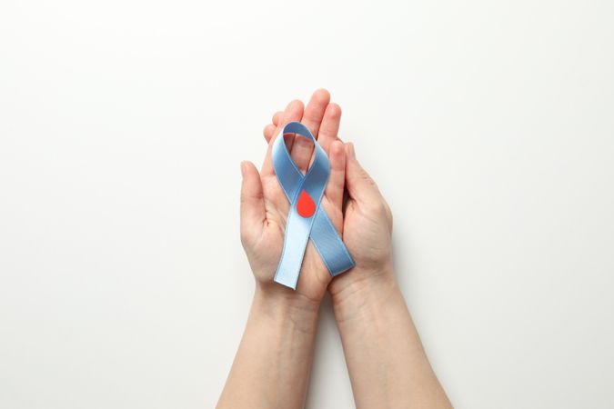 Female hands hold diabetes awareness ribbon on blank background