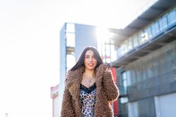 Cheerful woman wrapping in coat on street
