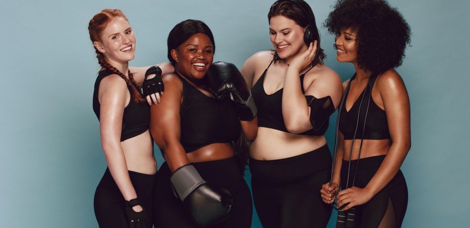 Diverse women with sports equipment looking at camera against grey background
