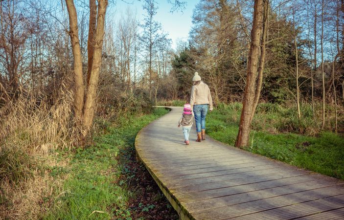 Mother and daughter walking along forest path together