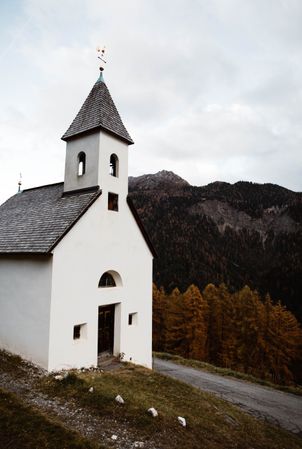 Small church on cliff near forest and mountains