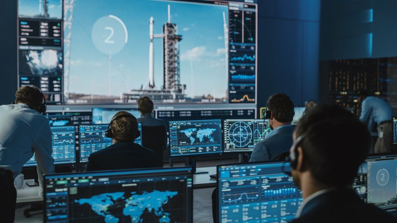 Mission Control Team Monitors Rocket Launch on Large Screens.