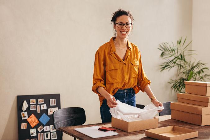 Young woman looking at camera and smiling at drop shipping business office at home