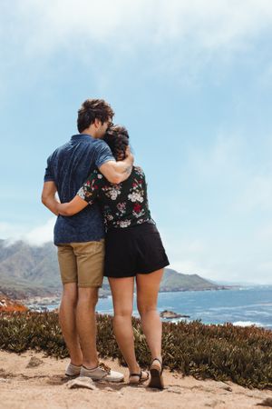 back view of amorous lovely couple embracing in big sur hill near sea