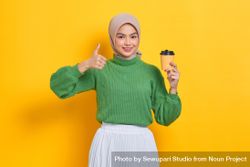 Woman in headscarf holding to go coffee cup and giving thumbs up sign 5QrDe4