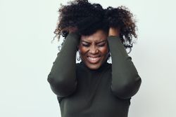 Black woman with her hands in her hair expressing annoyance
